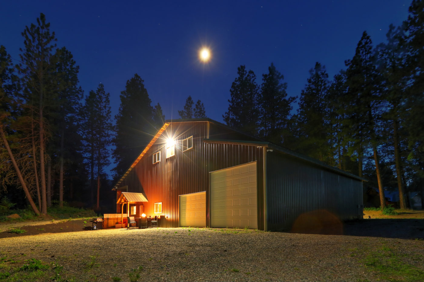 large metal barn at night with fire at round table and outdoor f